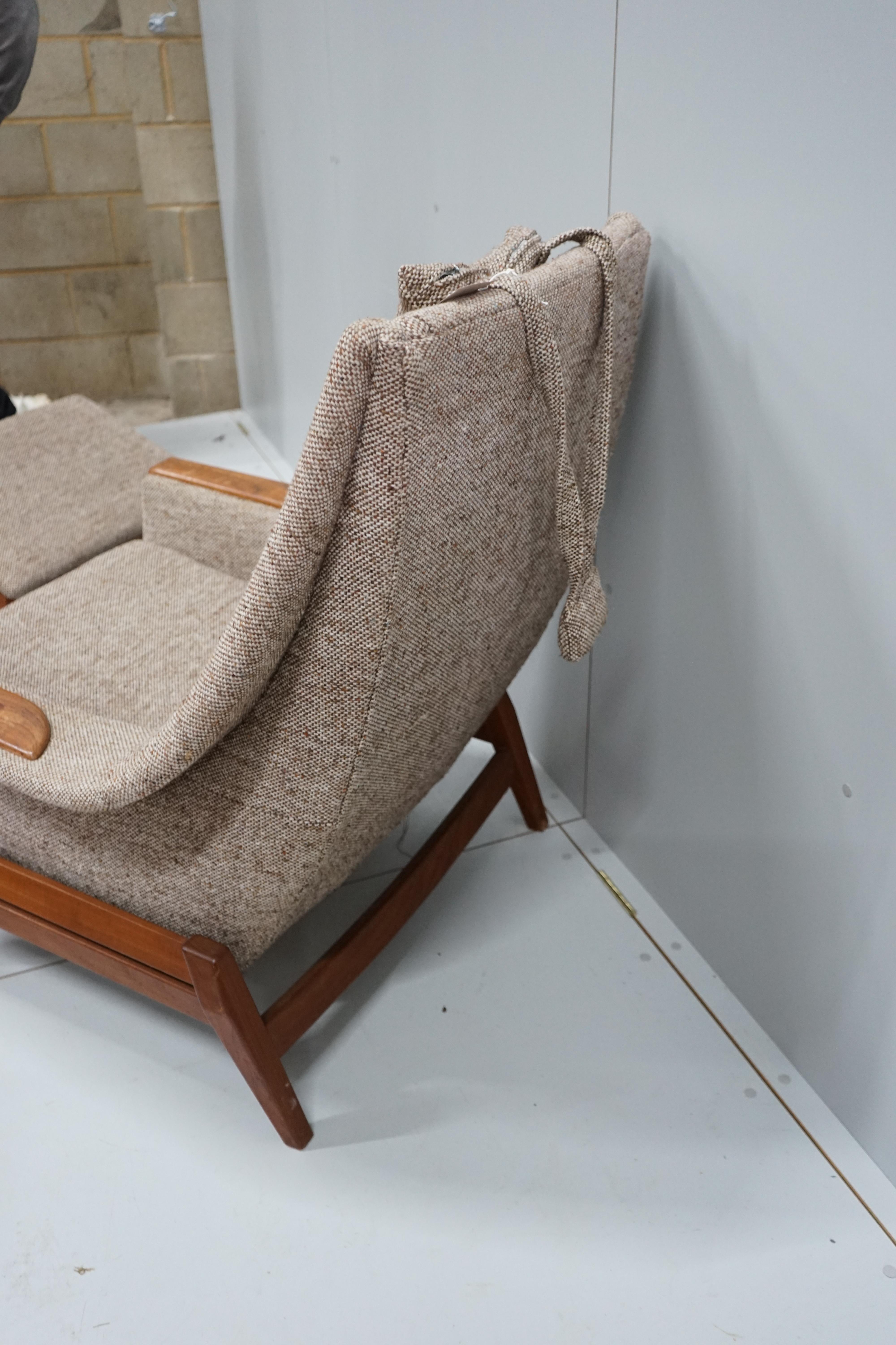 In the manner of Kofod Larsen, a mid century upholstered teak reclining armchair and adjustable foot stool, chair width 87cm, depth 86cm, height 102cm.